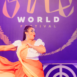 dancer in front of a "One World" wall
