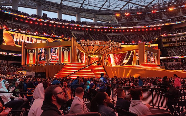 red and gold big wrestlemania stage with people in front of it