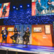 three men sitting on stools on a custom designed stage