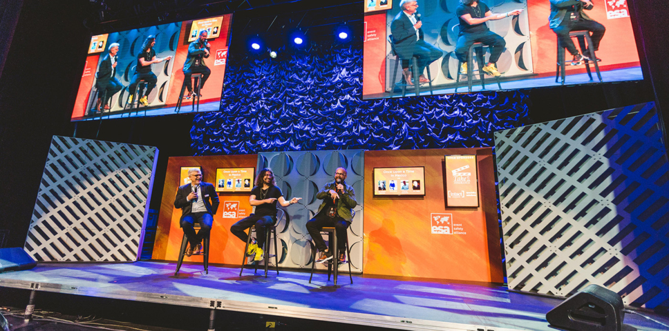 three men sitting on stools on a custom designed stage