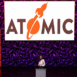person standing at a podium in front of large atomic backdrop