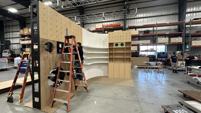 worker standing on a ladder while building custom set in workshop