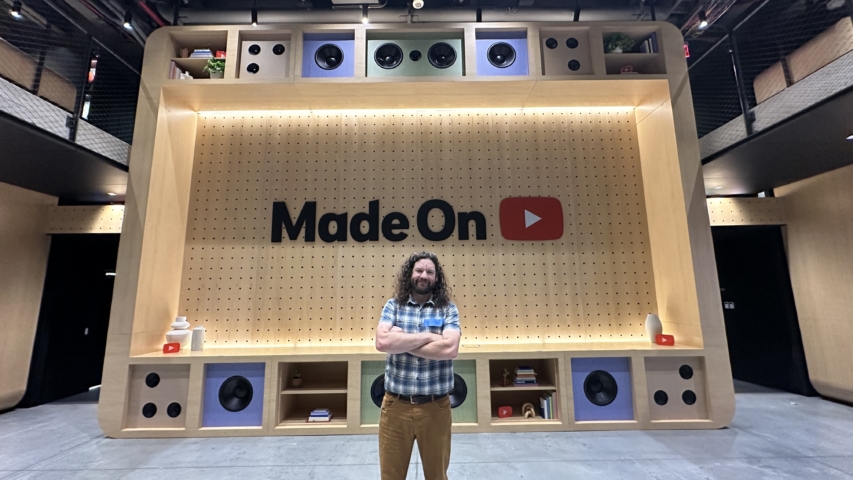 man with folded arms in front of 'made on youtube" display