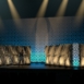 Rendering of a Shell modular scenic wall installed across a large stage with dramatic overhead lighting beams.