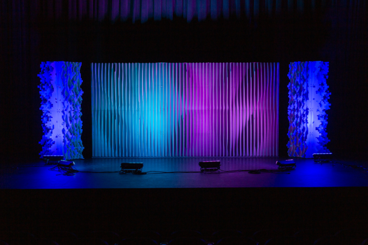 Full-width Shell and Pixel modular scenic wall installed on stage with blended blue and purple lighting.