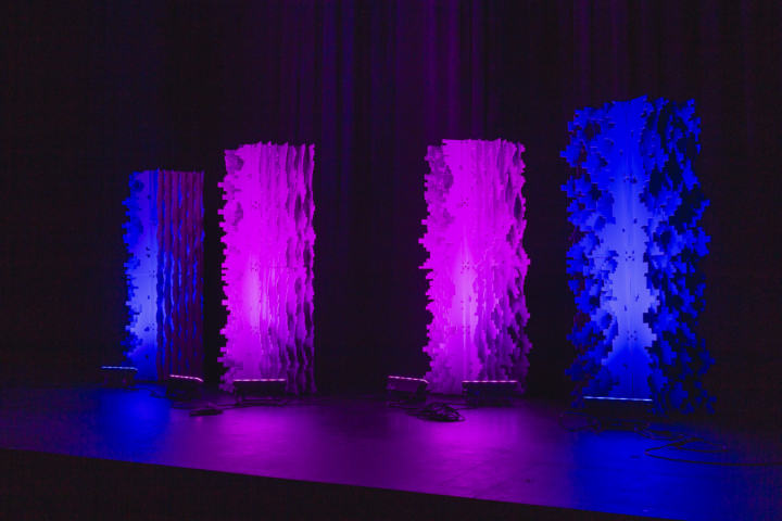 Pixel modular scenic panels installed on stage with strong vertical purple lighting columns.