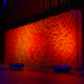 Angled view of a Pixel modular scenic wall installed on a stage and lit in warm red tones.
