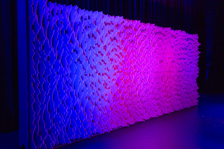 Angled Pixel modular scenic wall installed on a stage and lit with purple wash lighting.