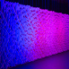 Angled Pixel modular scenic wall installed on a stage and lit with purple wash lighting.