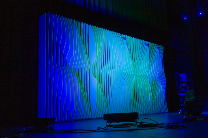 Angled view of Shell modular scenic wall installed on stage with colored lighting.