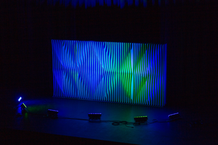 Full-width Shell modular scenic wall installed on a stage with blue and green lighting.