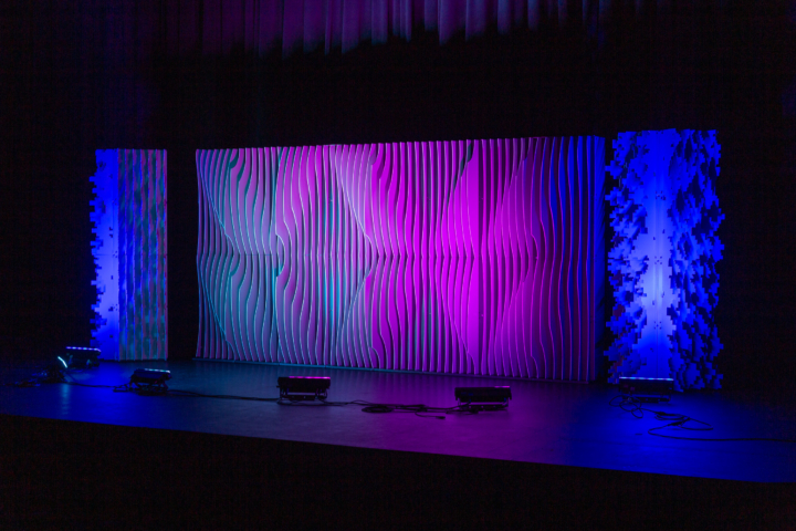 Full-width Pixel modular scenic wall installed on stage with blended purple, red, and blue lighting.